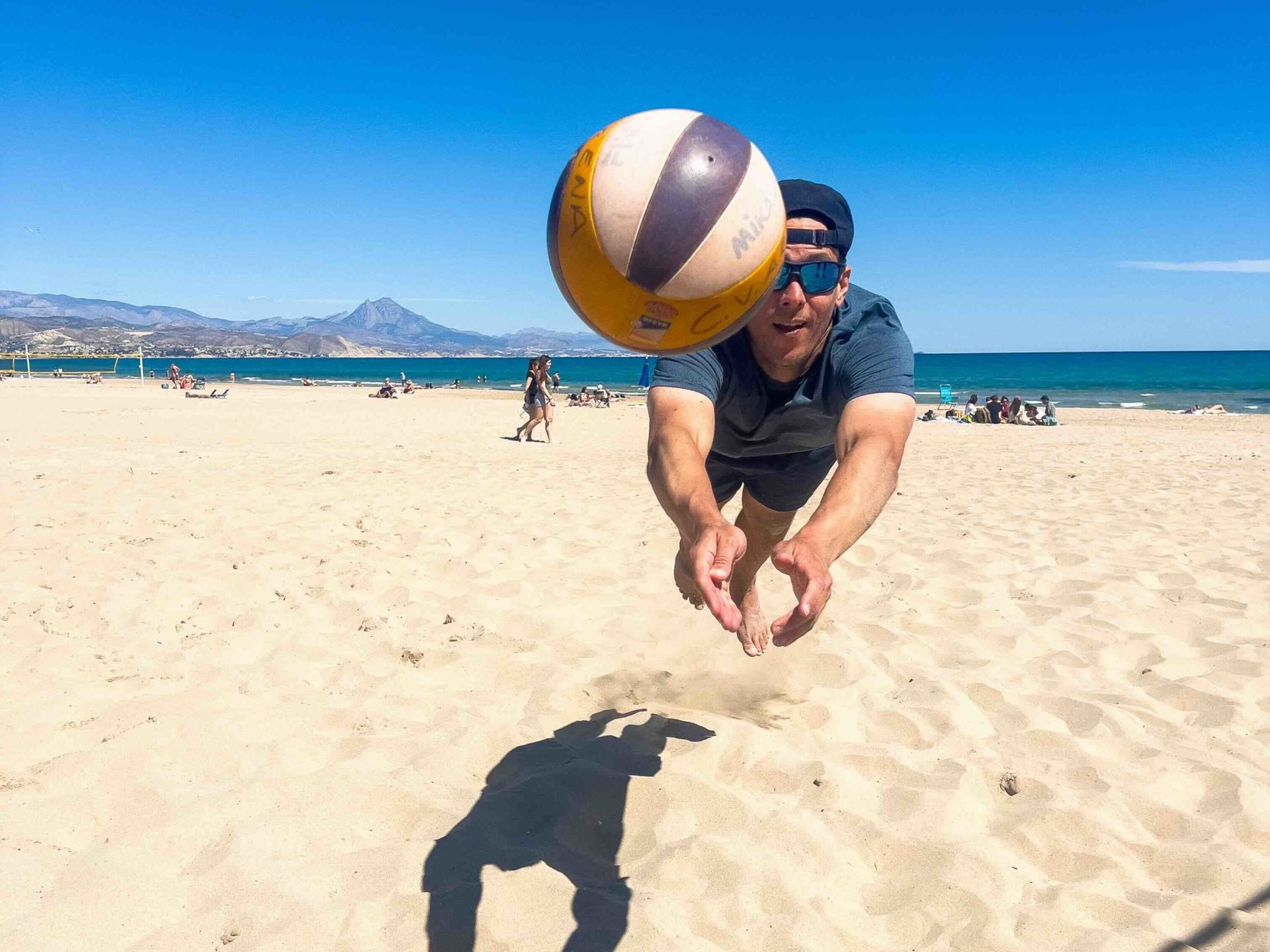 Matt Hodgkin diving to play beach volleyball on a sunny beach.