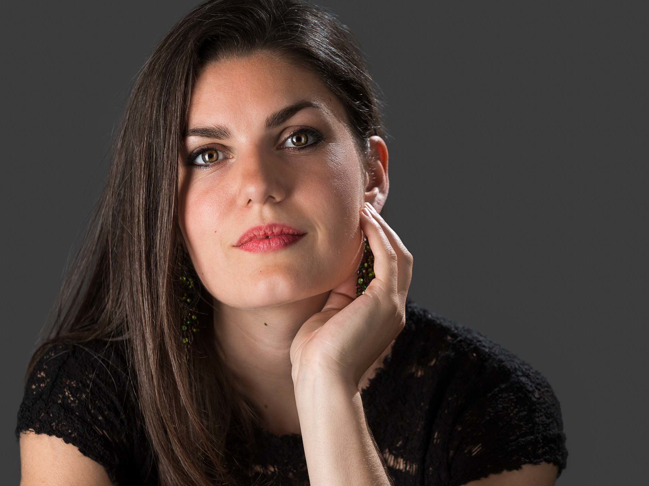 Professional studio portrait of a woman against a dark grey background.