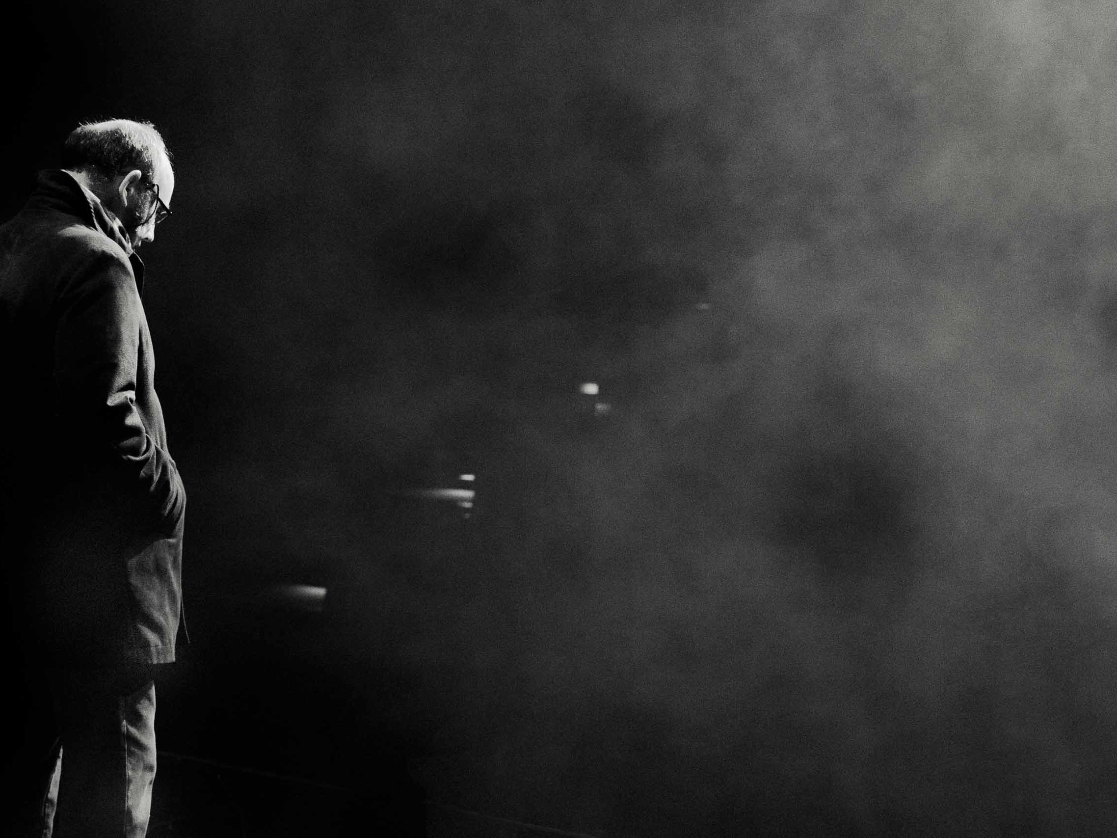 A performer standing backstage in dramatic light during a theatre production.